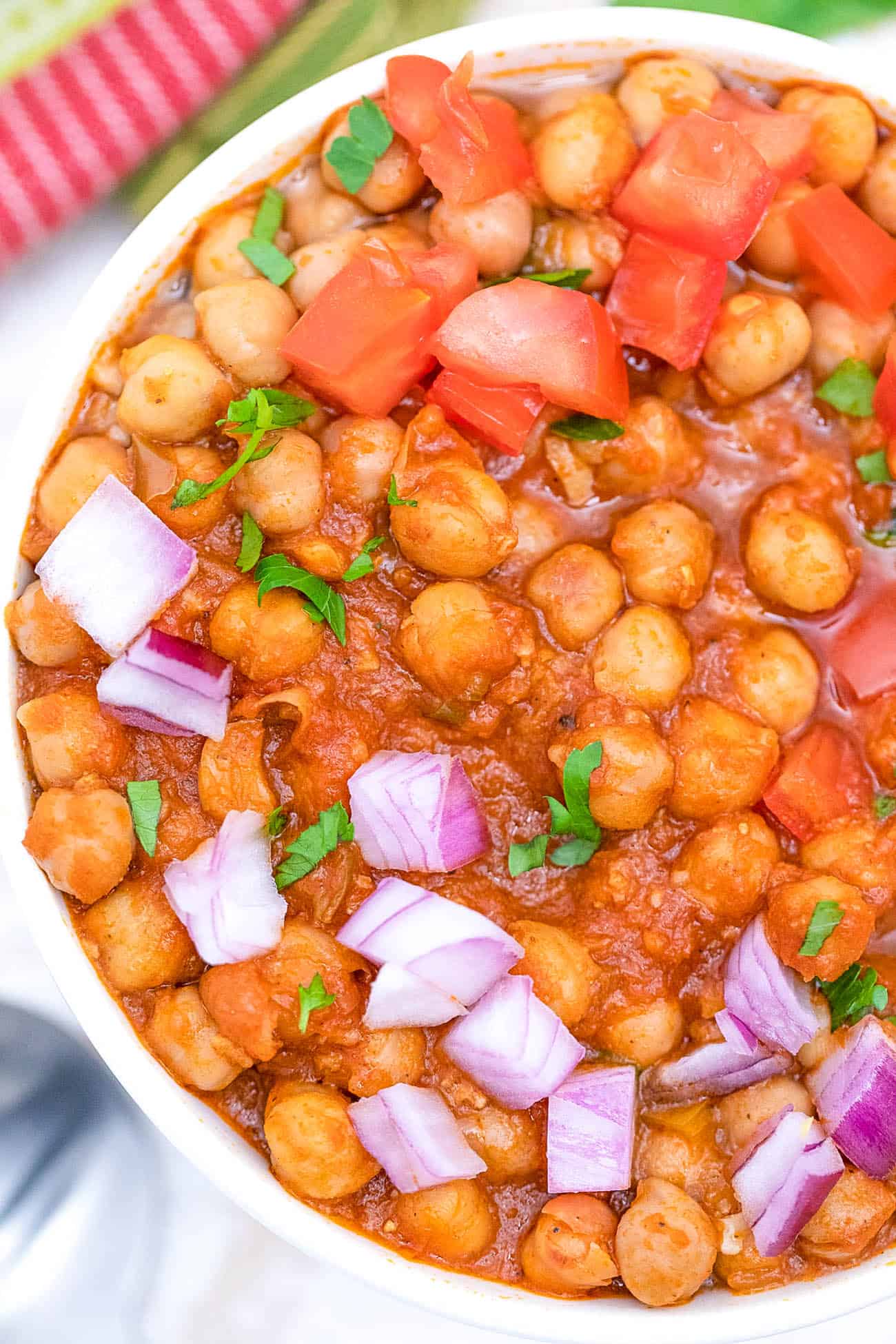 trader joe's channa masala recipe topped with tomatoes and onions, served in a white bowl