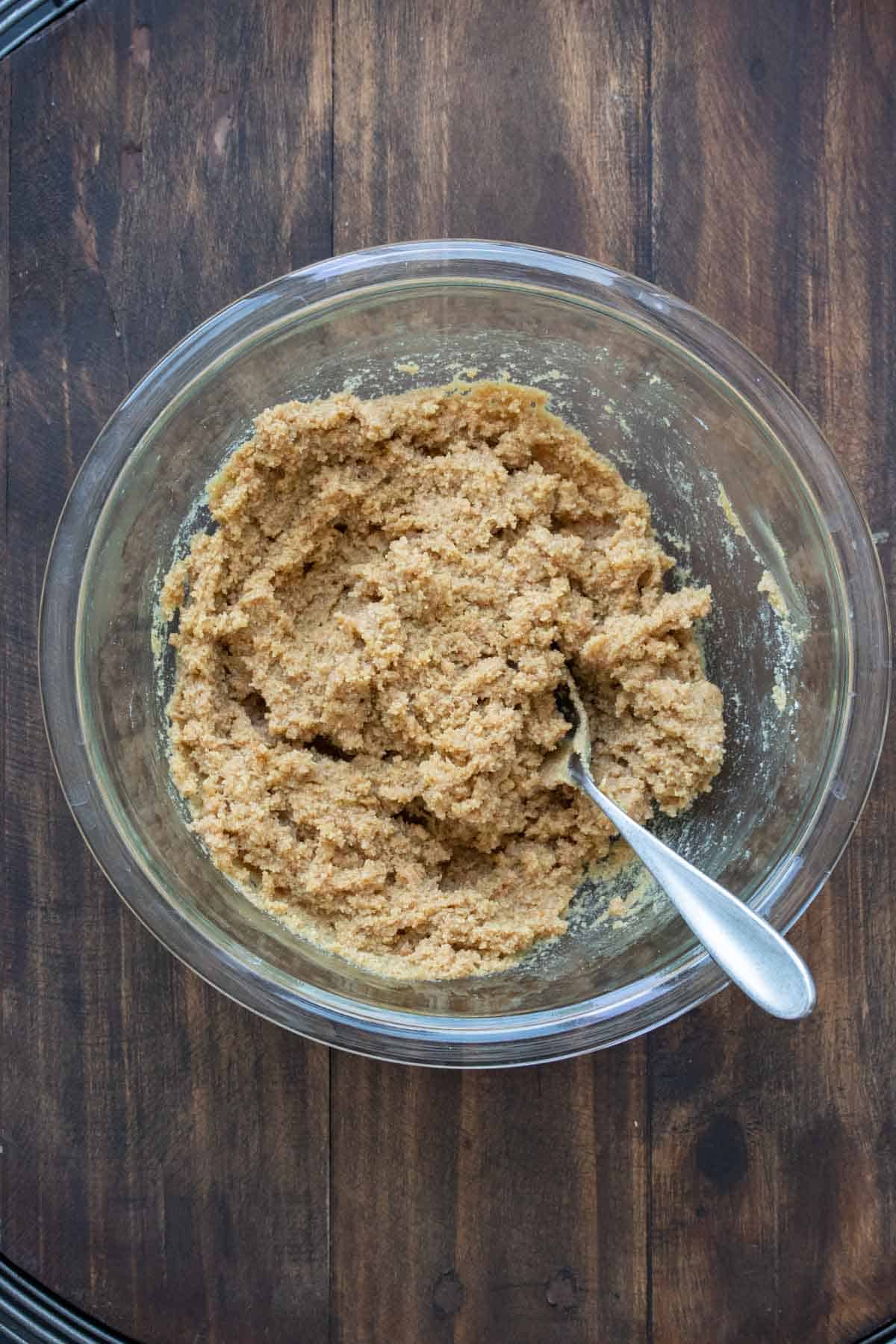 Bowl with cookie dough in it, on a wood background.