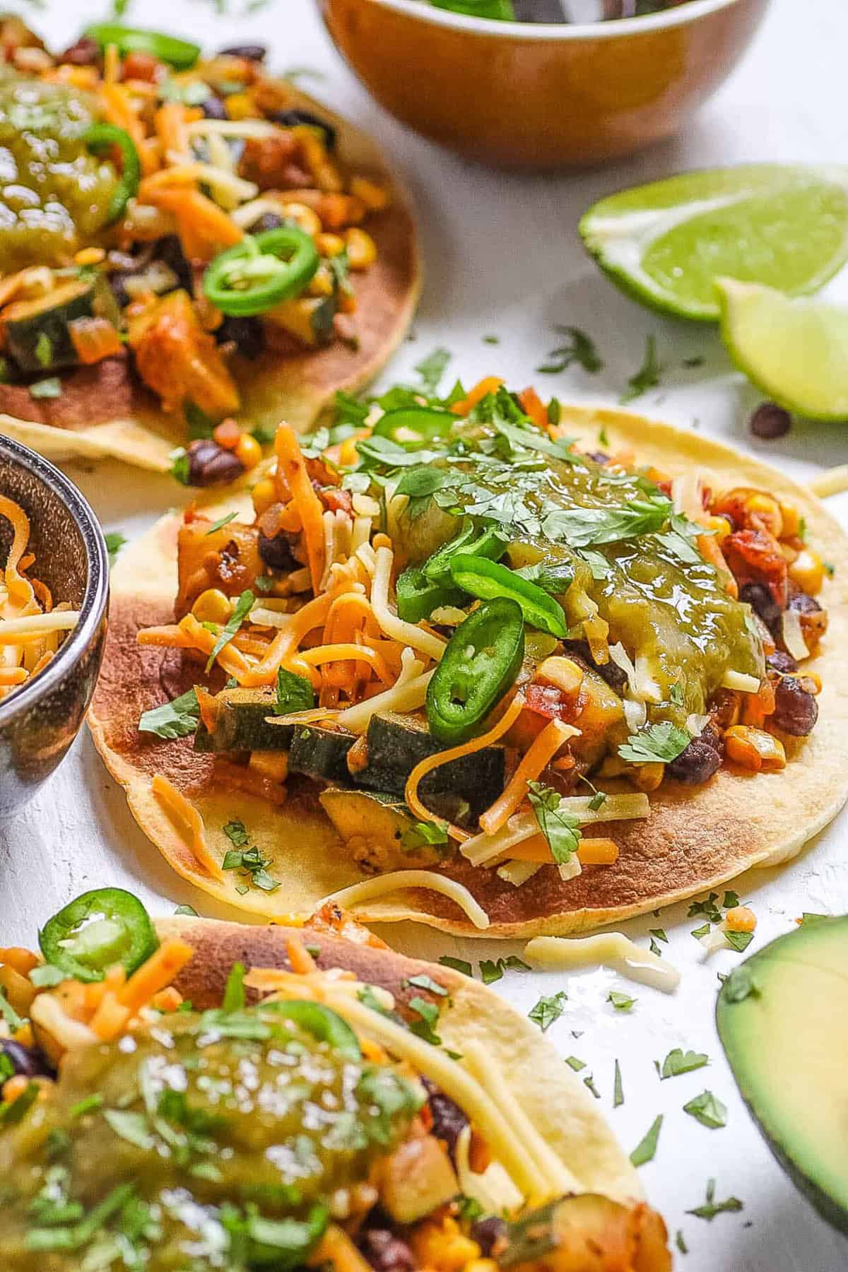 Black bean tostadas topped with corn, salsa, and veggies served on a white cutting board.