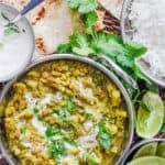 Lentil Cauilflower Curry served in a stainless steel pot with naan, cilantro and rice on the side