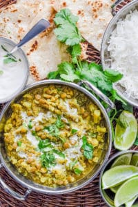 Lentil Cauilflower Curry served in a stainless steel pot with naan, cilantro and rice on the side
