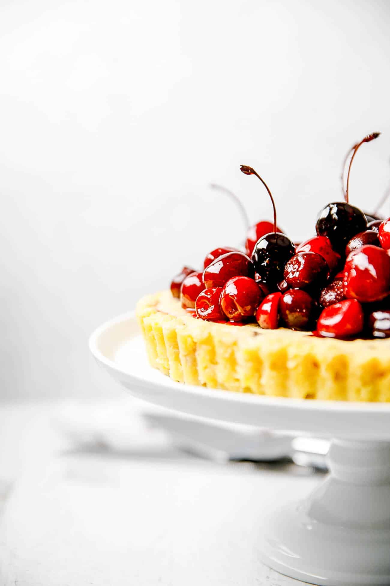 dark chocolate and ricotta pie, finished with fresh cherries, on a cake stand