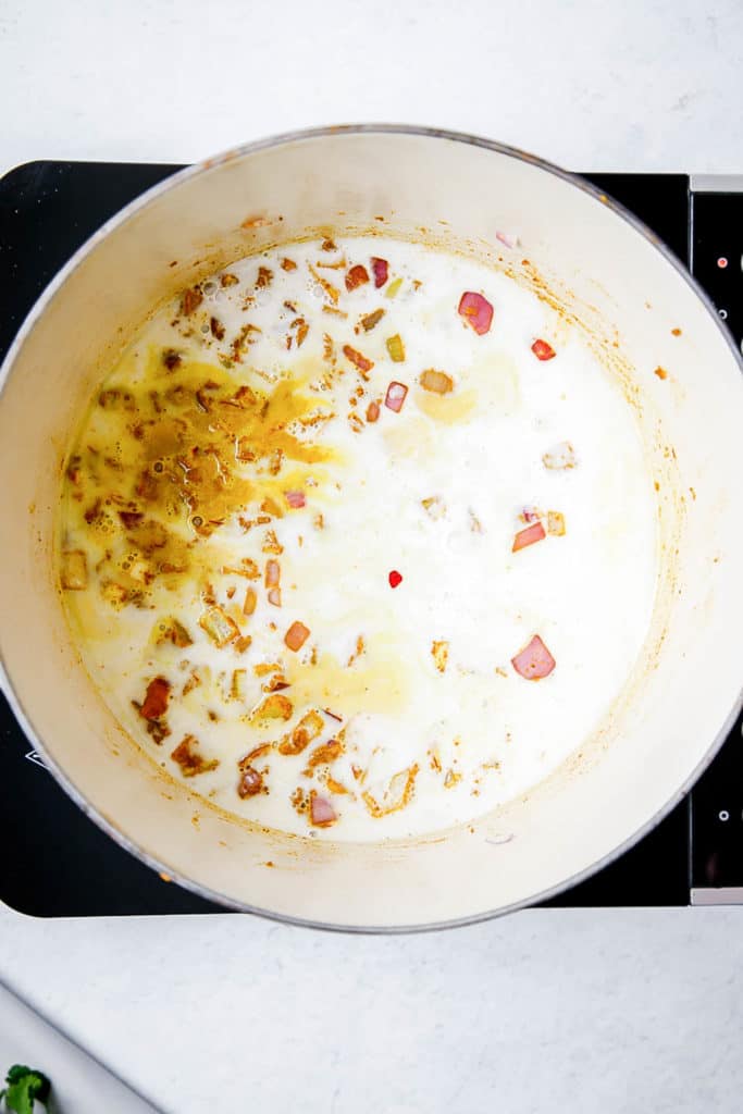 Onions and coconut milk cooking in a large pot.