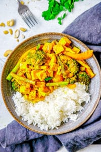 Tofu Yellow Curry with Veggies and Cashews served in a grey bowl with white rice