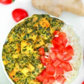 vegan palak paneer served with tomatoes and rice in a white bowl