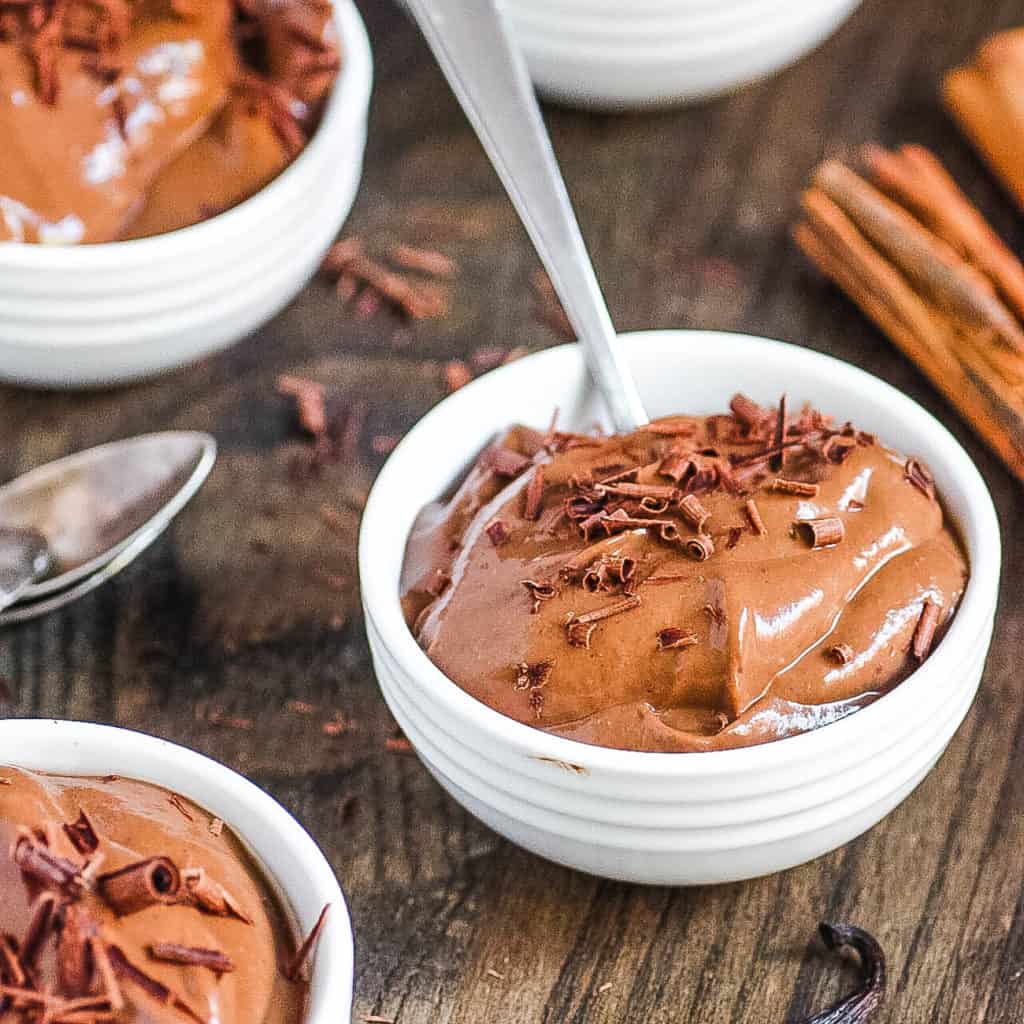 Healthy chocolate almond milk pudding served in white bowls topped with chocolate shavings.