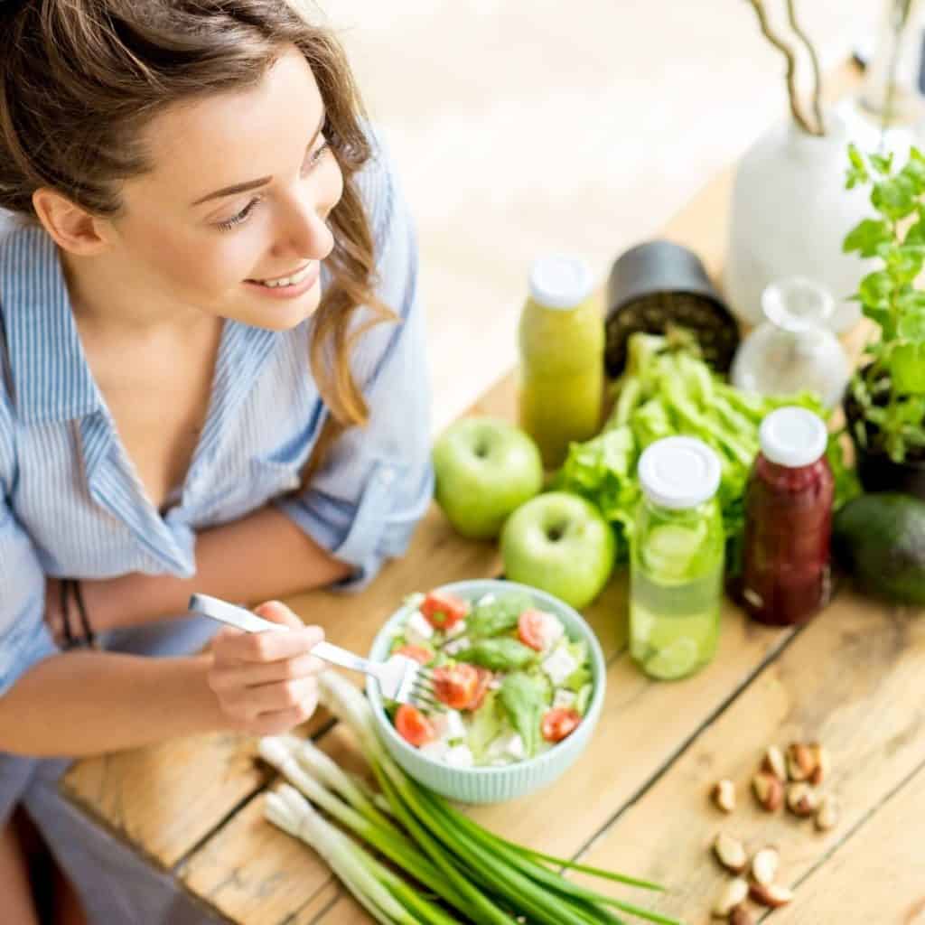 woman eating a salad as part of steps to a healthy lifestyle