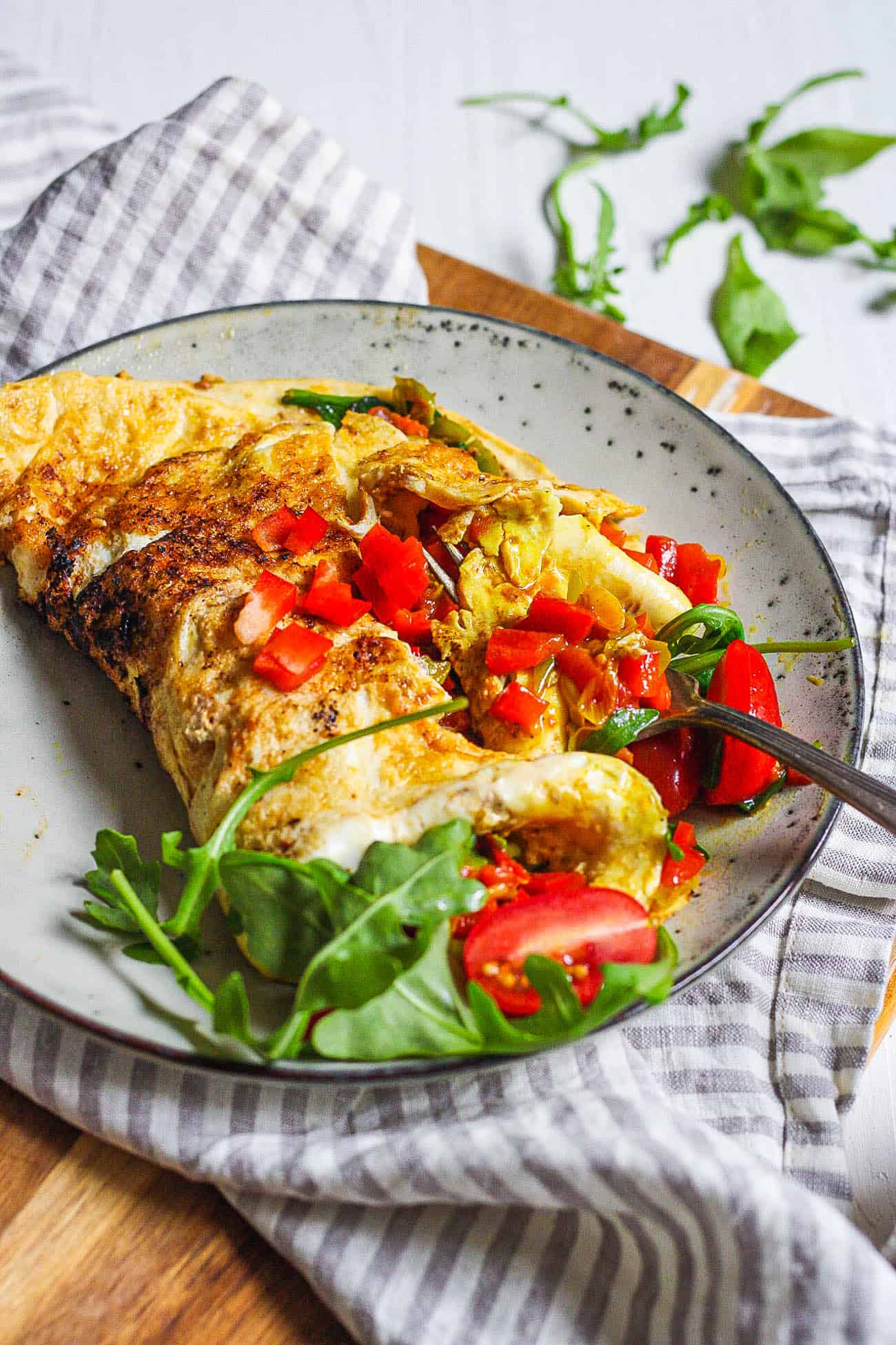 low calorie omelette with indian spices and veggies served on a grey plate