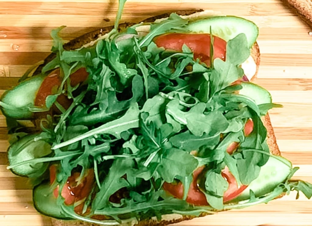bread topped with cucumber, tomato, and arugula
