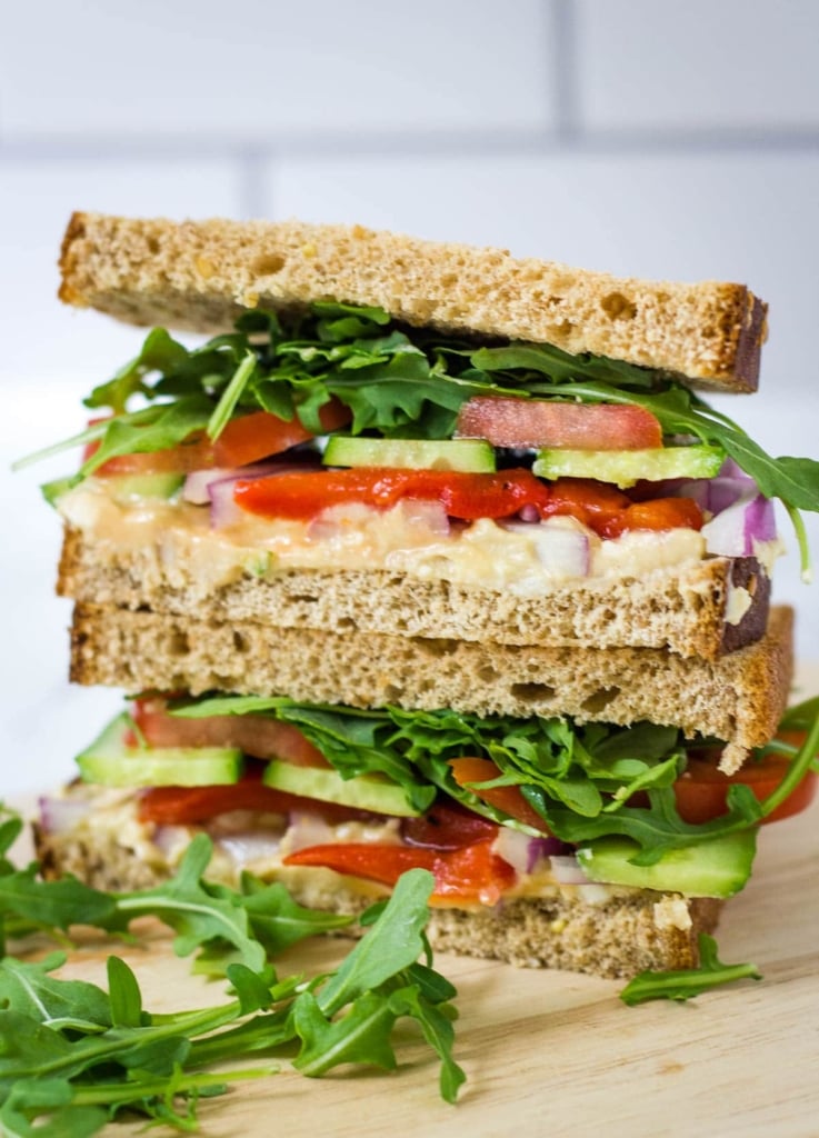 veggie sandwich with arugula, tomato, cucumber, red onion, hummus, and red pepper on whole wheat