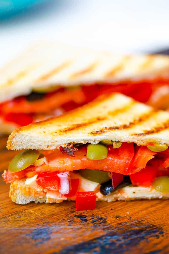 mediterranean sandwich cut in half on a wooden cutting board