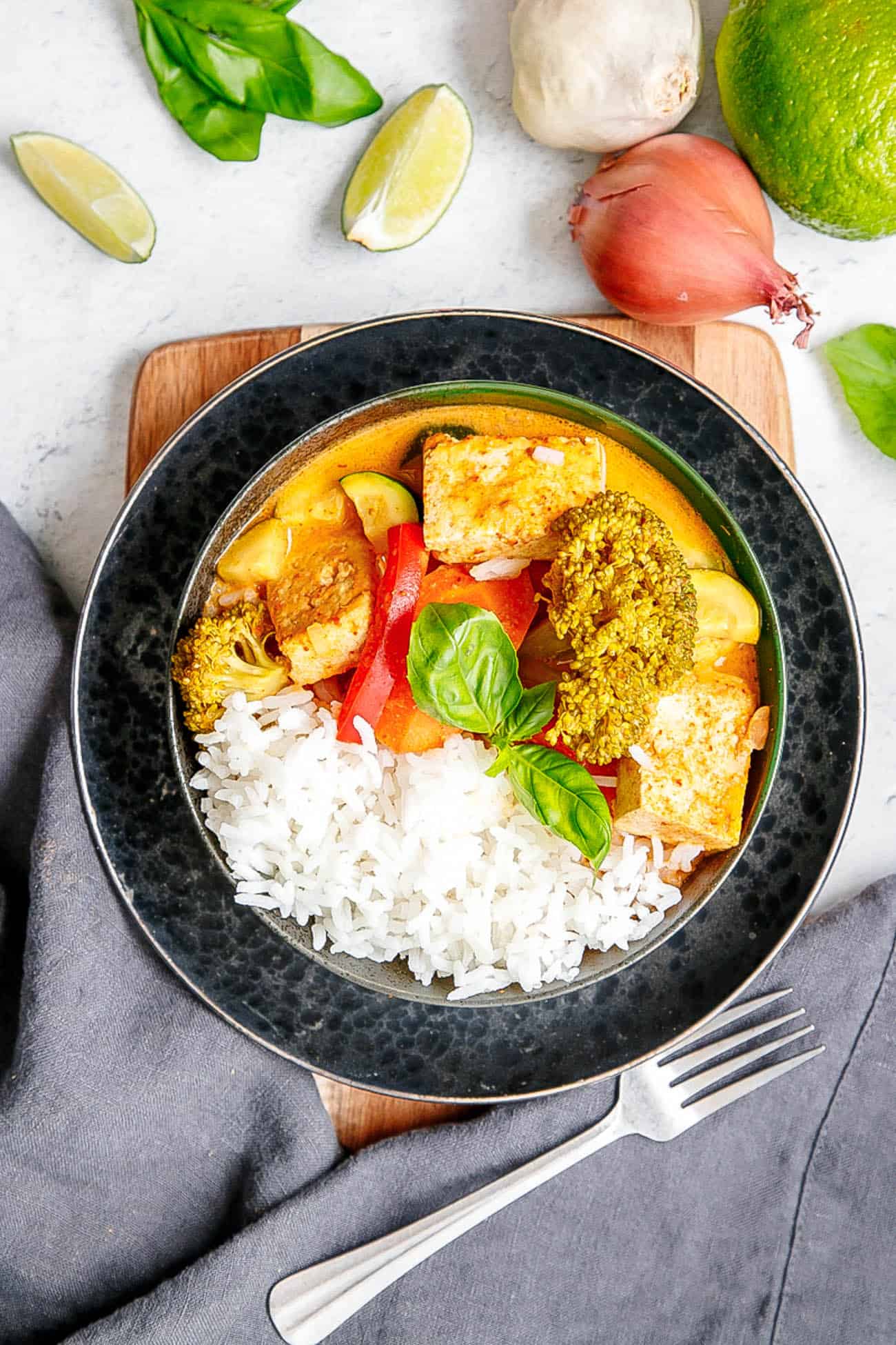 vegan panang curry in a black bowl with fresh herbs and rice