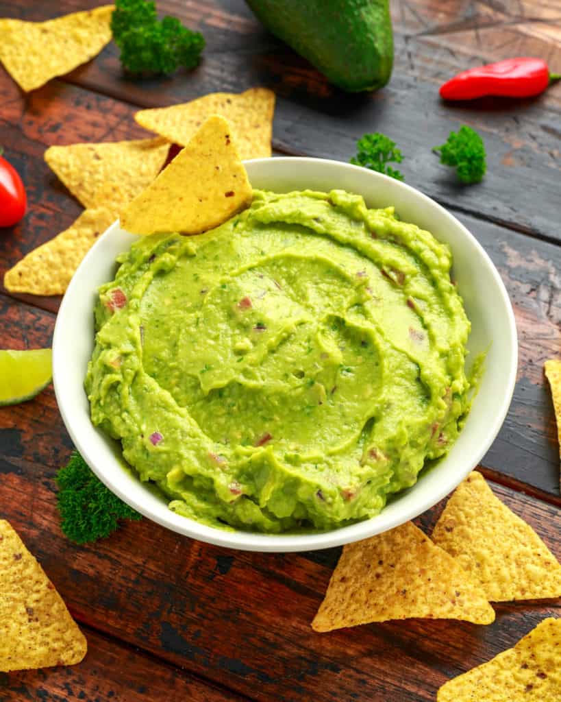 vegan guacamole with tortilla chips in a white bowl