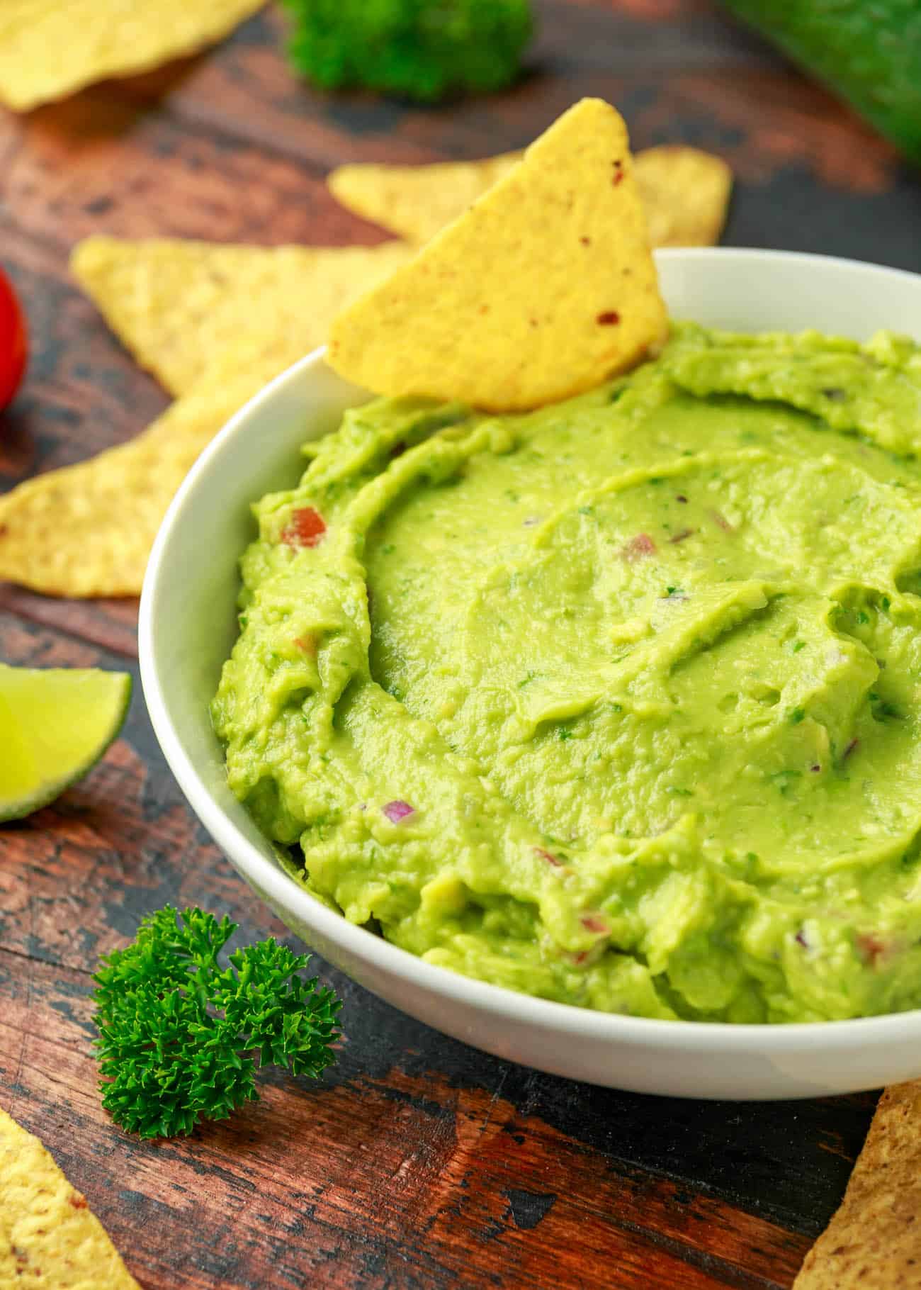 vegan guacamole with tortilla chips in a white bowl