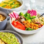 vegan lunch ideas - Vegan lunch table. Chocolate smoothie bowl, Buddha bowl with tofu, chickpeas and quinoa, lentil soup and toasts on a gray background.
