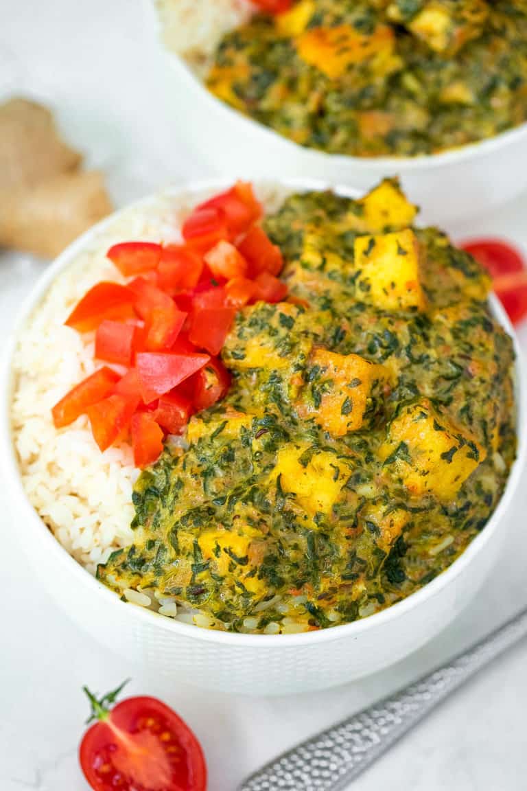 vegan palak paneer served with tomatoes and rice in a white bowl