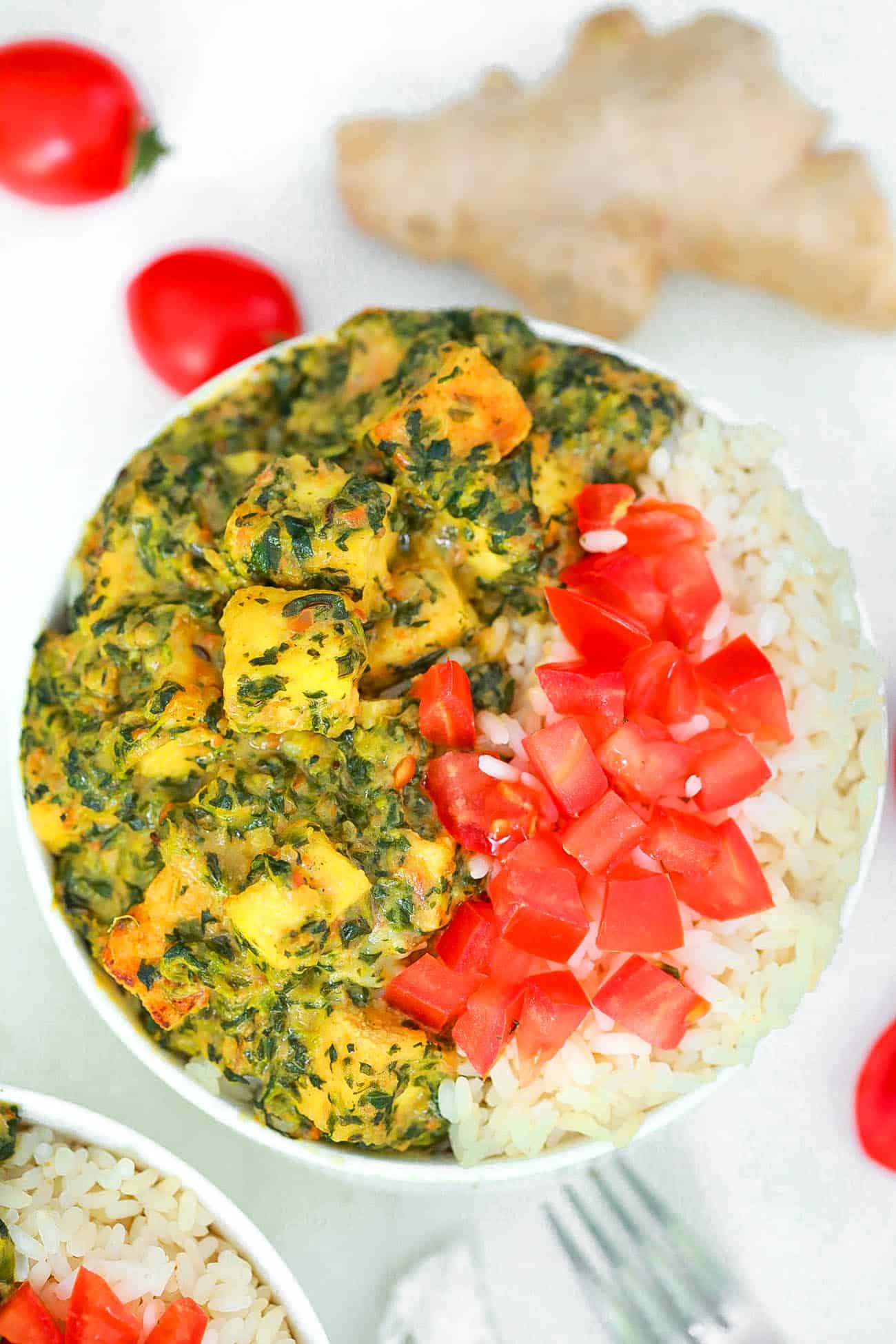 vegan palak paneer served with tomatoes and rice in a white bowl