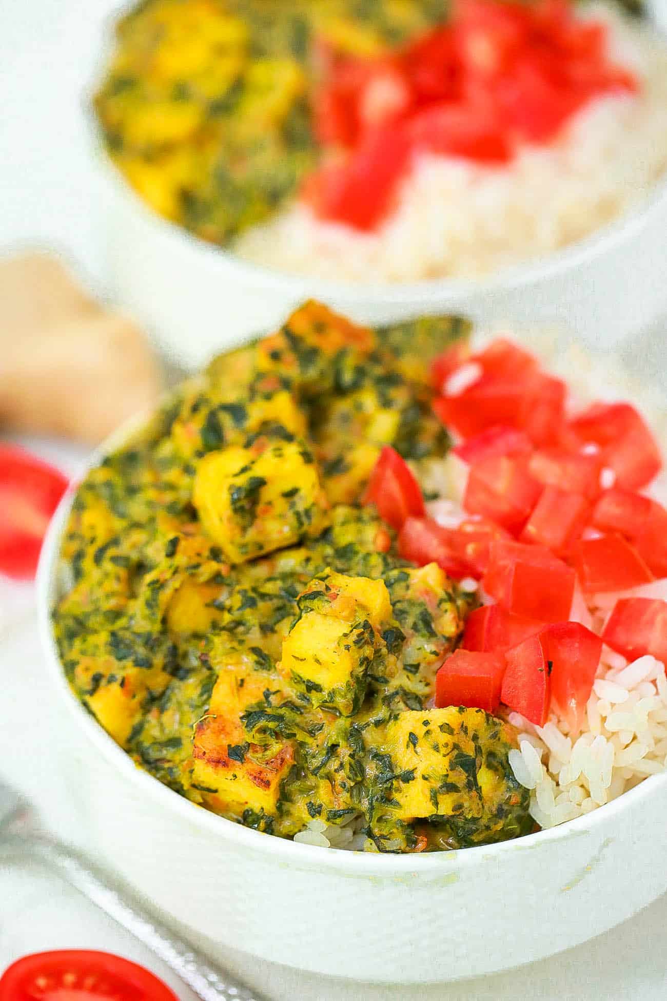 vegan palak paneer served with tomatoes and rice in a white bowl