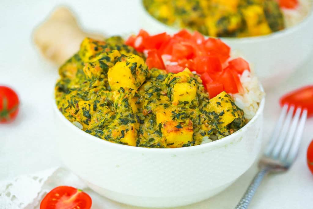 vegan palak paneer served with tomatoes and rice in a white bowl