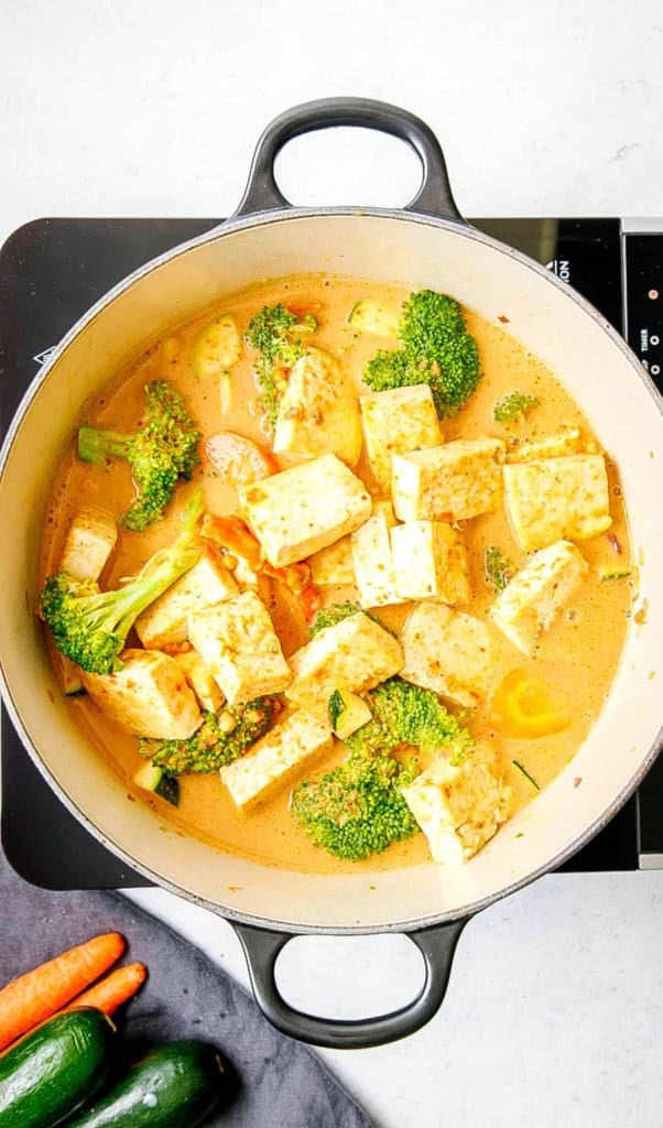 Tofu panang curry cooking in a pot on the stove.