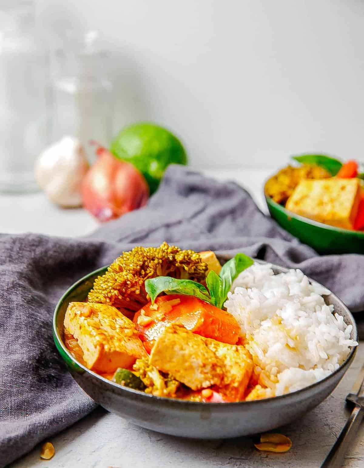 Vegan panang curry with tofu and rice served in a grey bowl.
