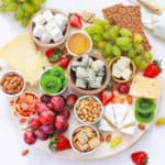 vegetarian cheese board served on a wooden platter with cheeses, fruits, nuts, condiments, crackers