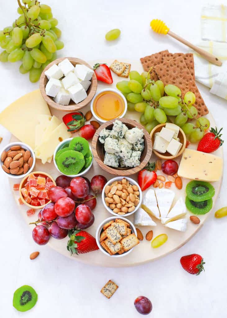 vegetarian cheese board served on a wooden platter with cheeses, fruits, nuts, condiments, crackers