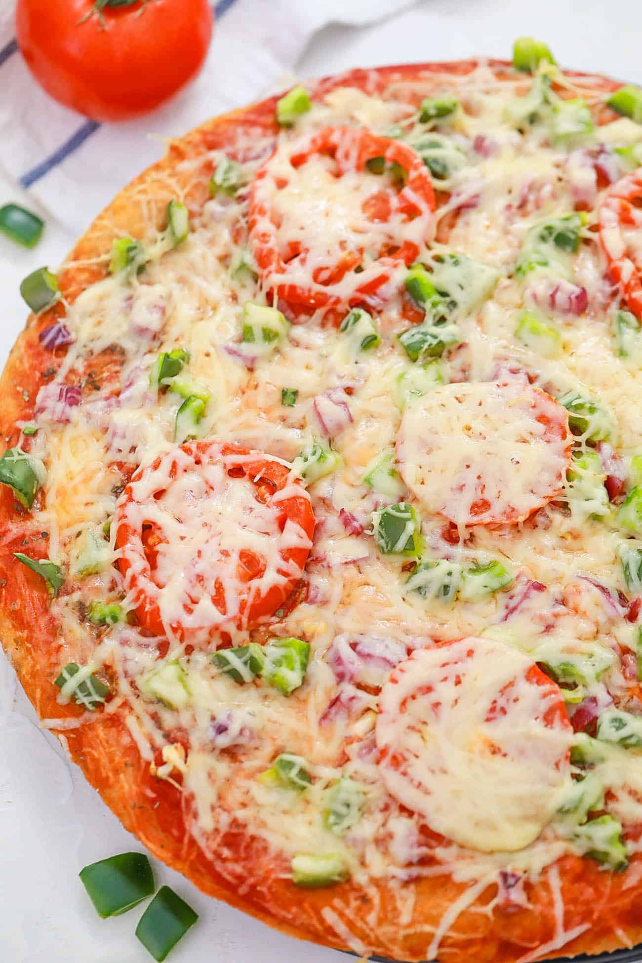 veggie pizza recipe topped with fresh veggies cheese and sauce served on a white plate