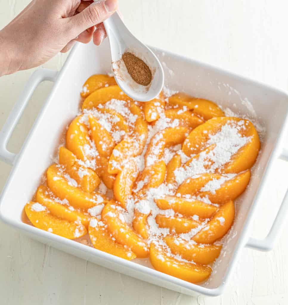 cinnamon added to peaches in baking dish