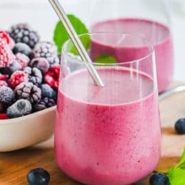 berry smoothie in a glass with a metal straw