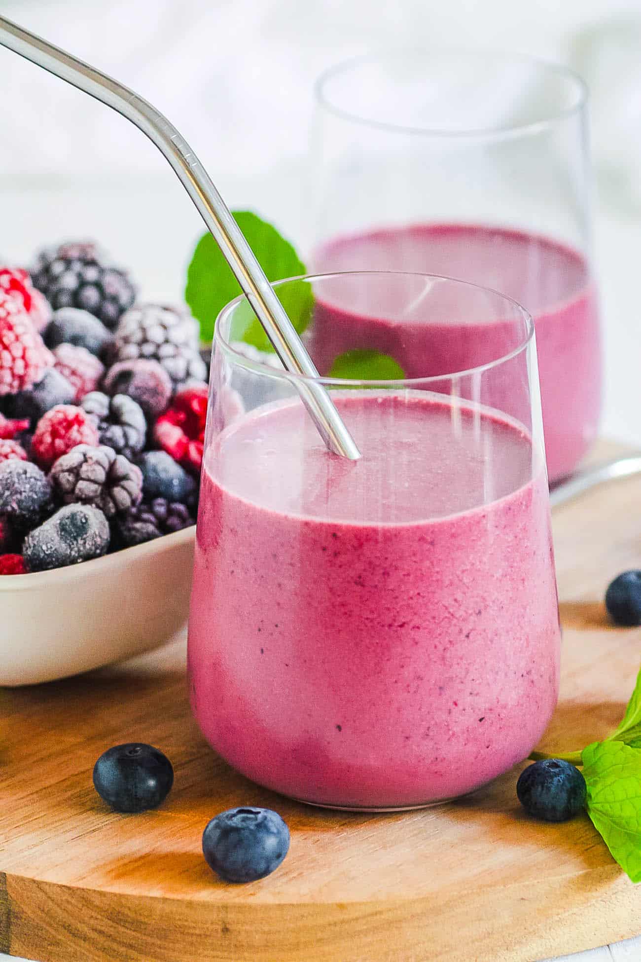 berry smoothie in a glass with a metal straw