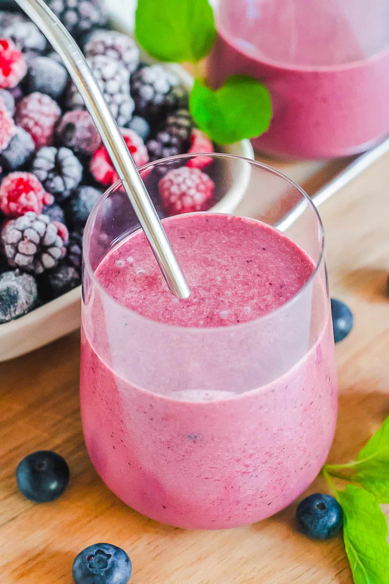 berry smoothie in a glass with a metal straw