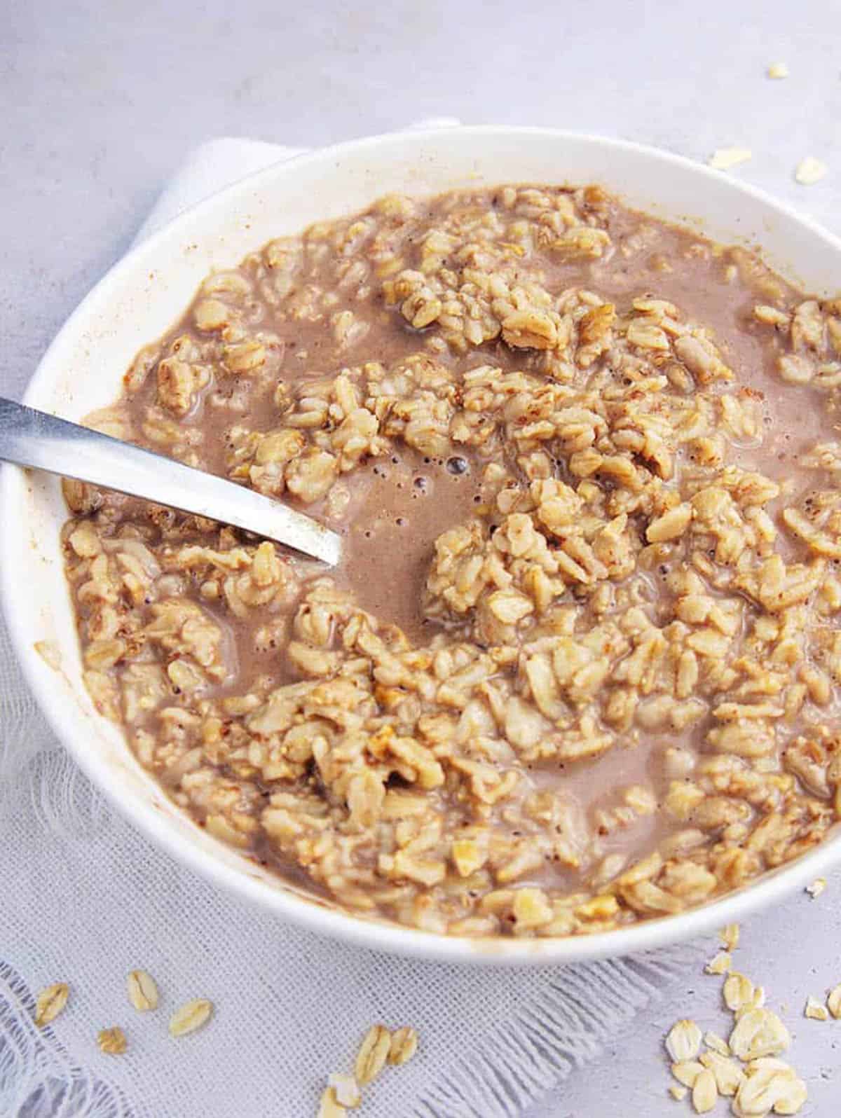 Healthy chocolate oatmeal in a white bowl with a spoon.