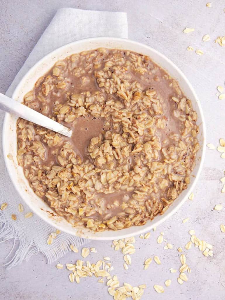 Healthy chocolate oatmeal for picky eaters in a white bowl with a spoon.