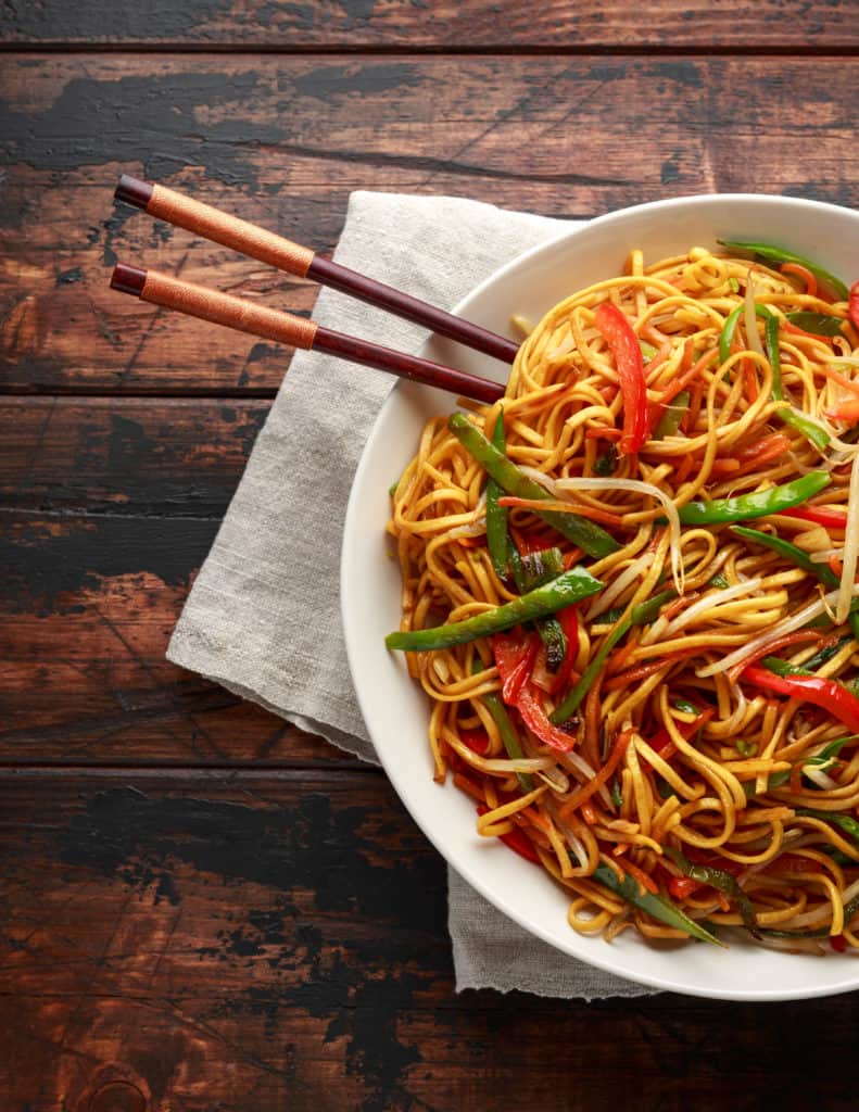 foods that start with c - Chow mein, noodles and vegetables dish with wooden chopsticks 