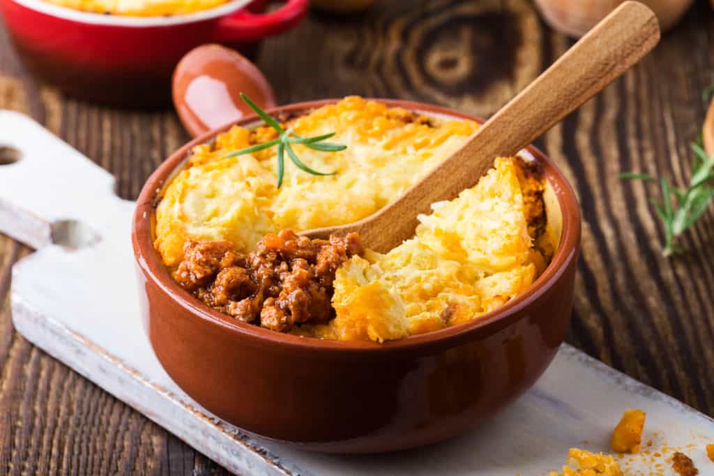 Shepherd's pie, traditional British dish with  minced meat and mashed potato on rustic wooden table 
