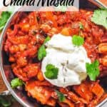 Chana masla in pot topped with yogurt and herbs.