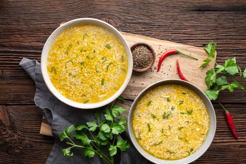 Quick and simple ،y egg drop soup with parsley and chilli on rustic wooden background