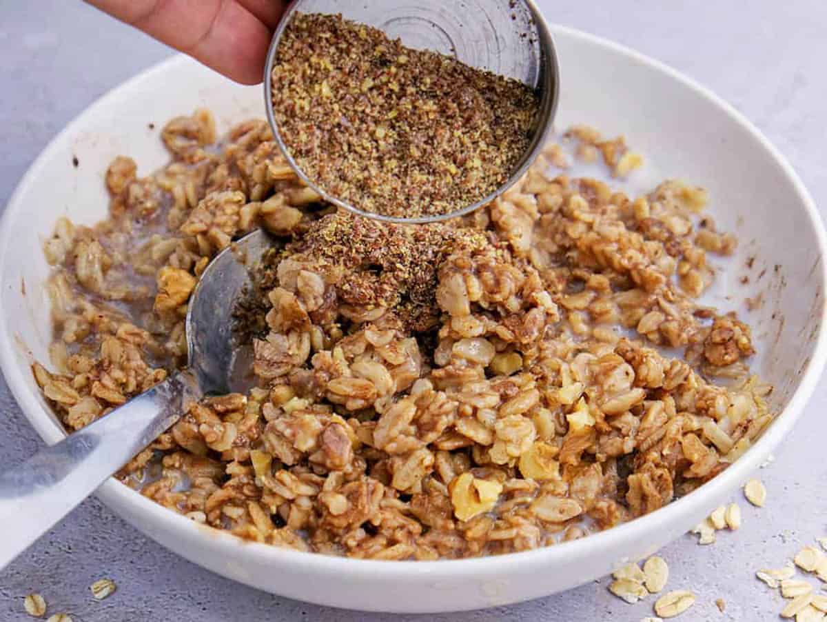 Ground flaxseeds added to a bowl of oats.