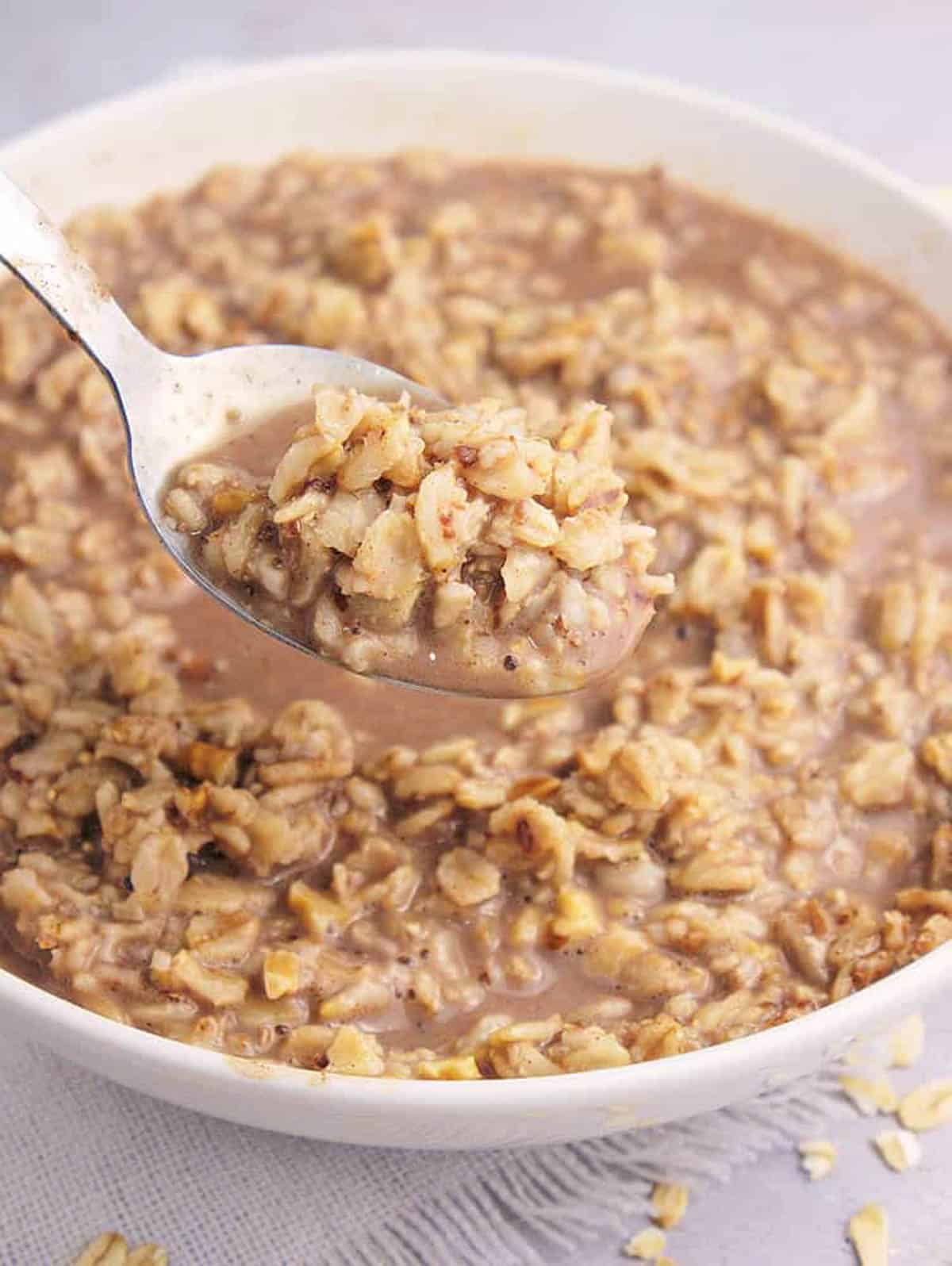 Chocolate oats in a white bowl with a spoonful of oats taken out.