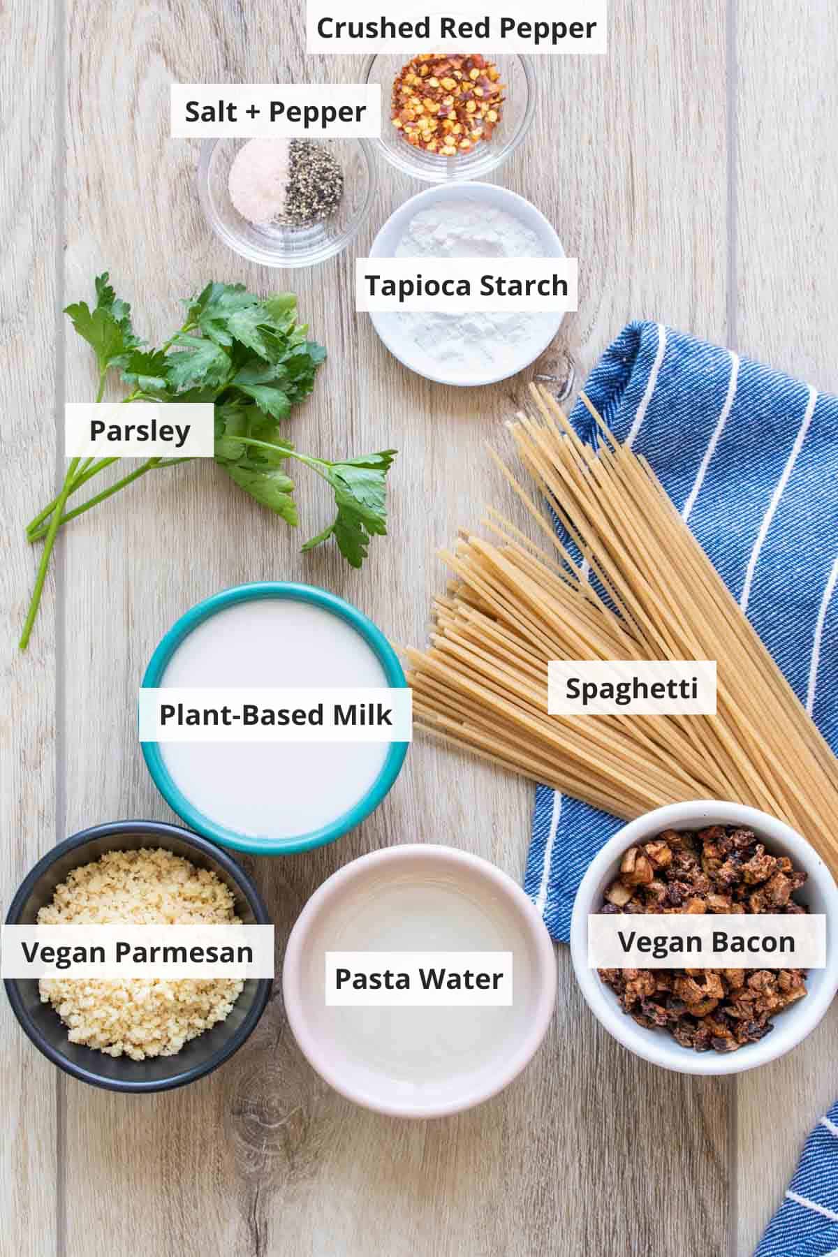 Ingredients for vegan carbonara recipe on a wood countertop.