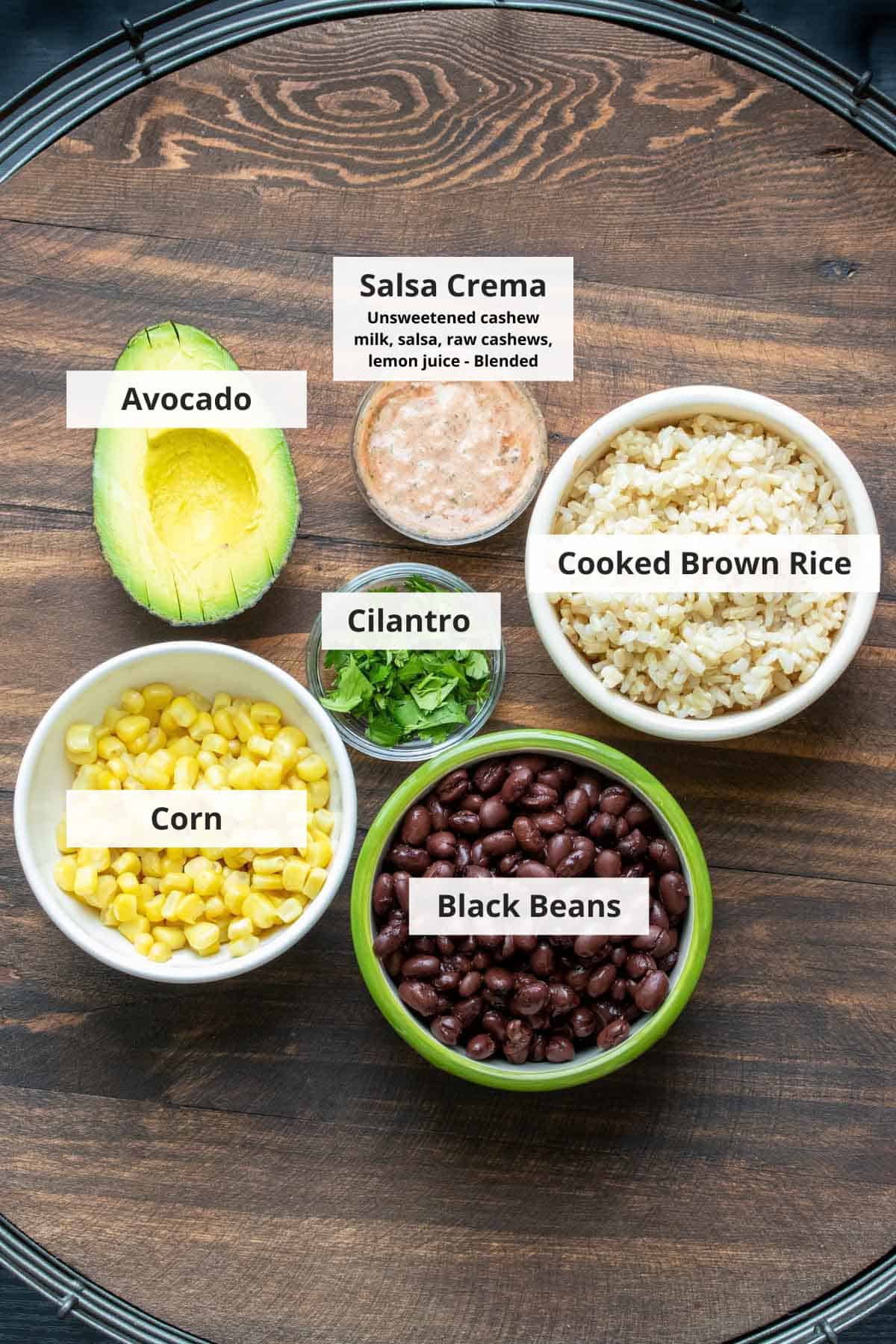 Ingredients for vegan rice and black bean burritos on a wood background.