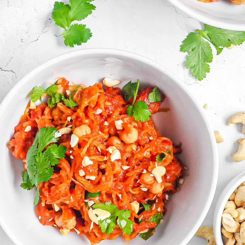 keto spaghetti squash tossed with spices herbs and cashews in a white bowl