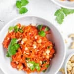 keto spaghetti squash tossed with spices herbs and cashews in a white bowl