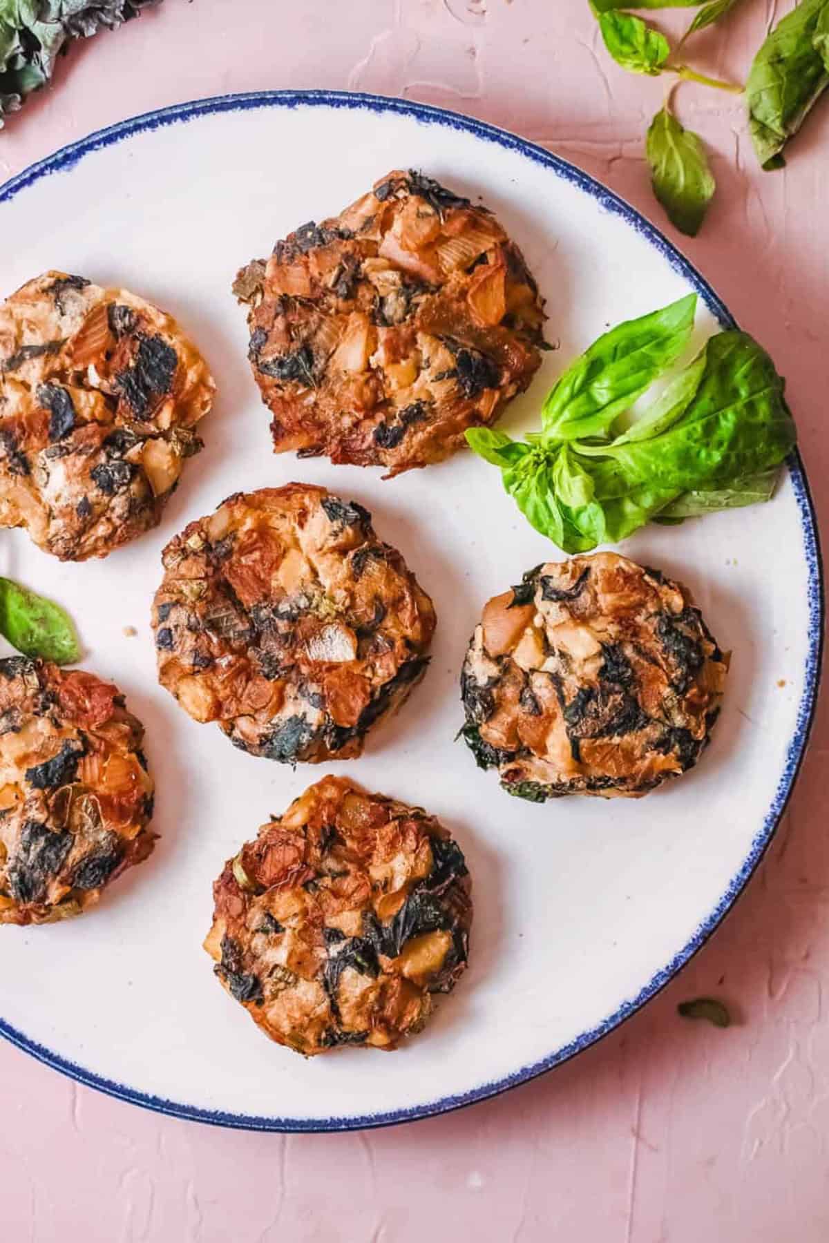 Mashed potato fritters with kale and onions served on a white plate.