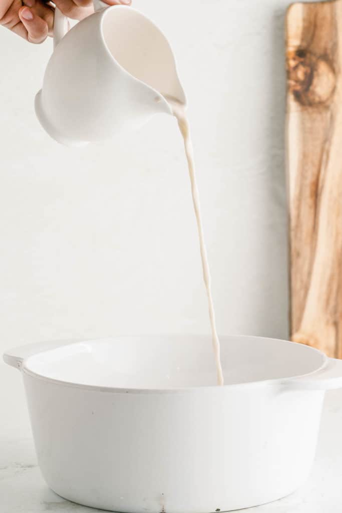 Pouring almond milk into a white pot.