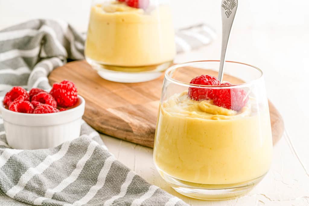 Cups of vegan vanilla pudding topped with raspberries.