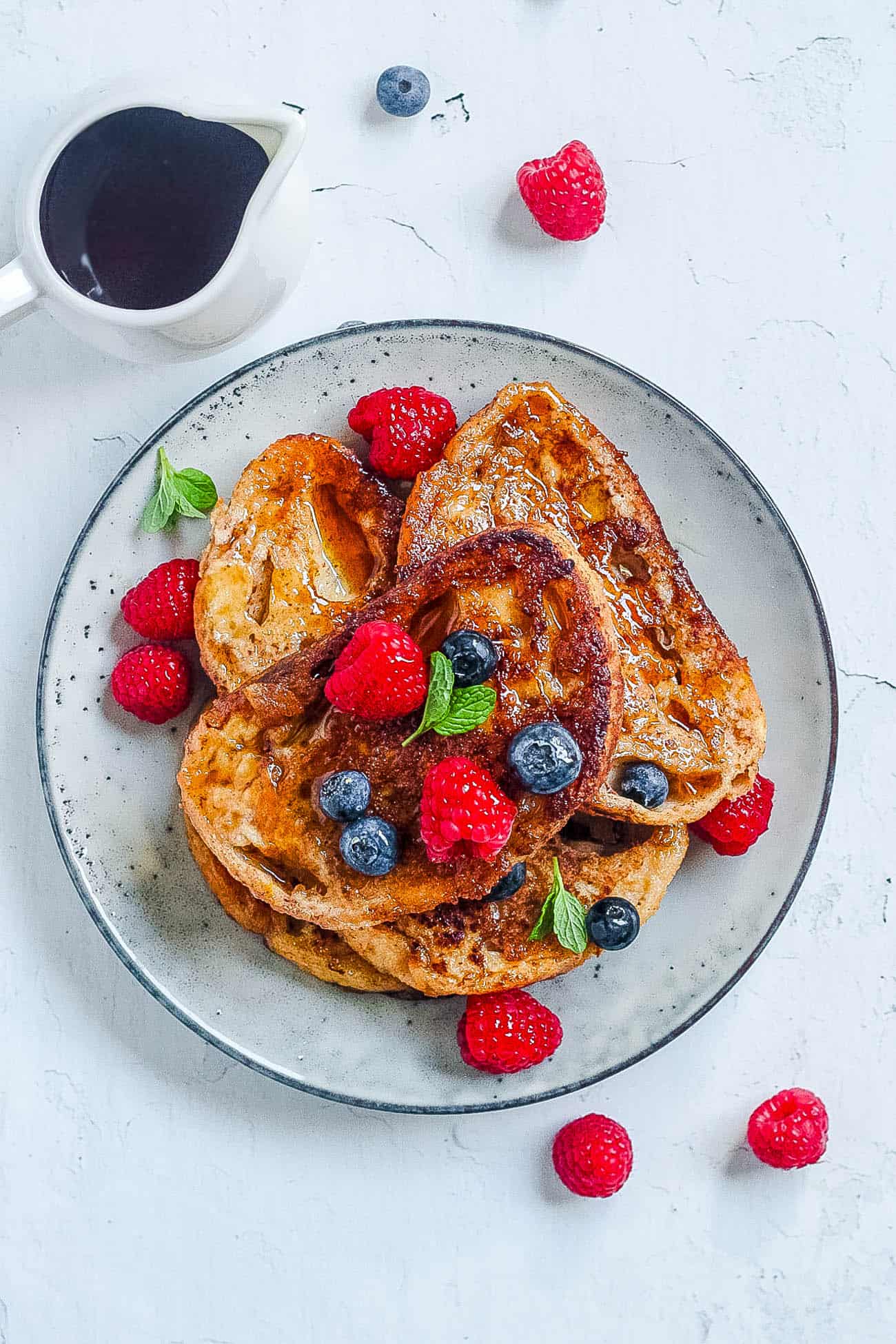 easy low calorie healthy french toast with berries and syrup served on a white plate
