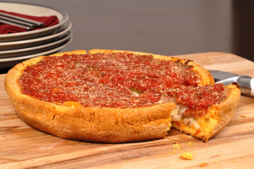 A Chicago style deep dish pizza with a piece cut out