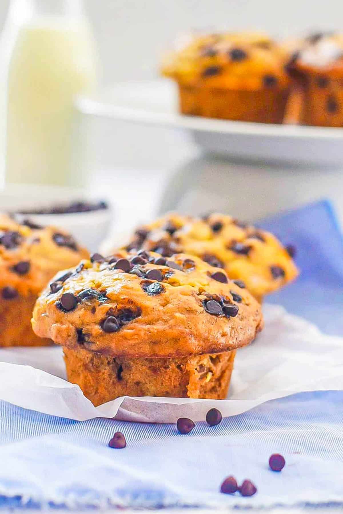 Gluten free banana chocolate chip muffins on parchment paper on top of a blue napkin.